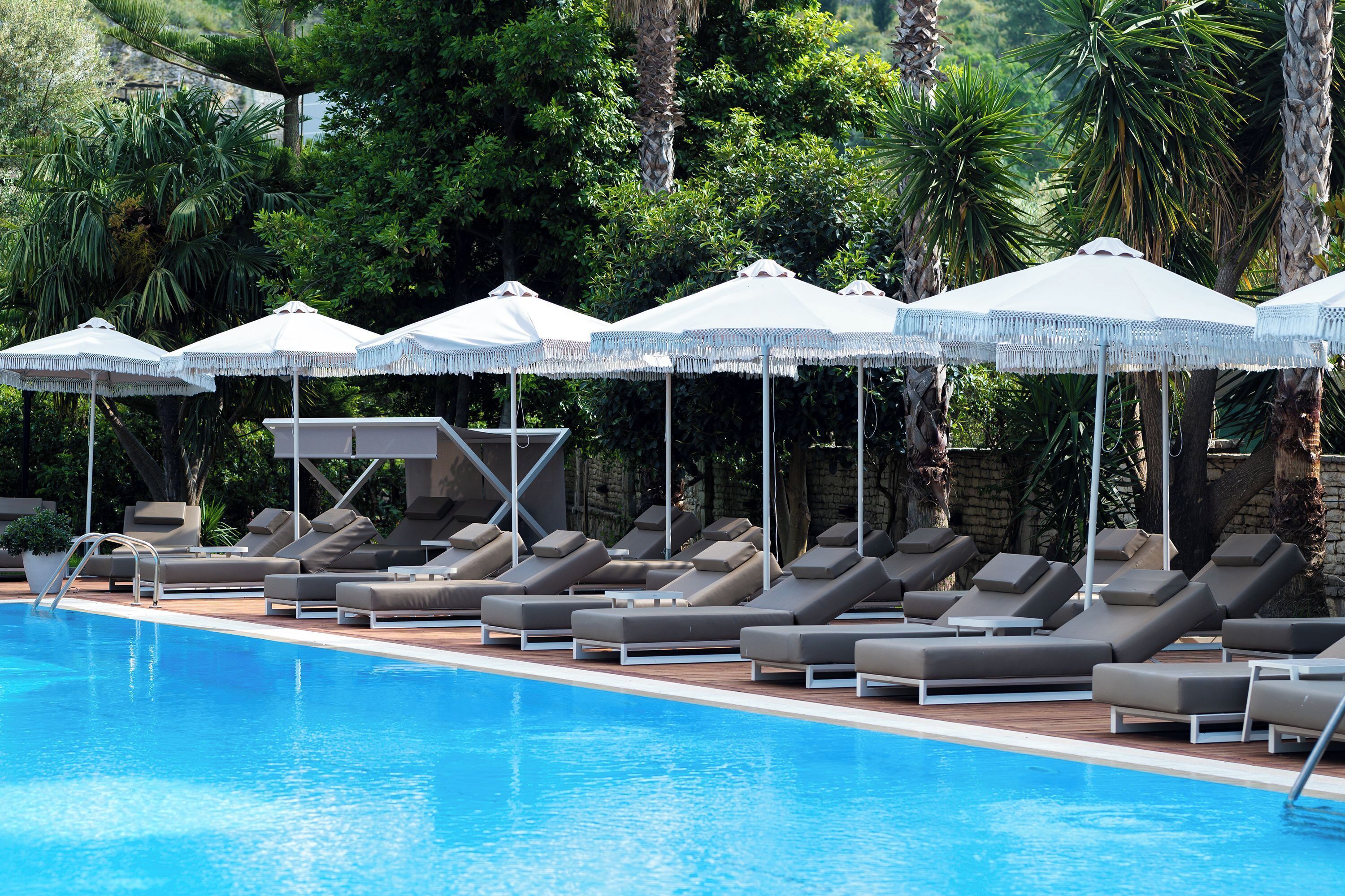 Un área junto a la piscina con sillones de descanso y sombrillas.