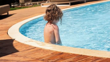 Una piscina al aire libre de temporada, sombrillas