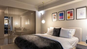 A modern bedroom with a large bed, a bedside table, and a wall-mounted light fixture.