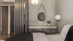 Une chambre d’hôtel moderne avec un grand lit, un bureau avec un miroir, un miroir rond, une lampe de chevet et une porte coulissante.