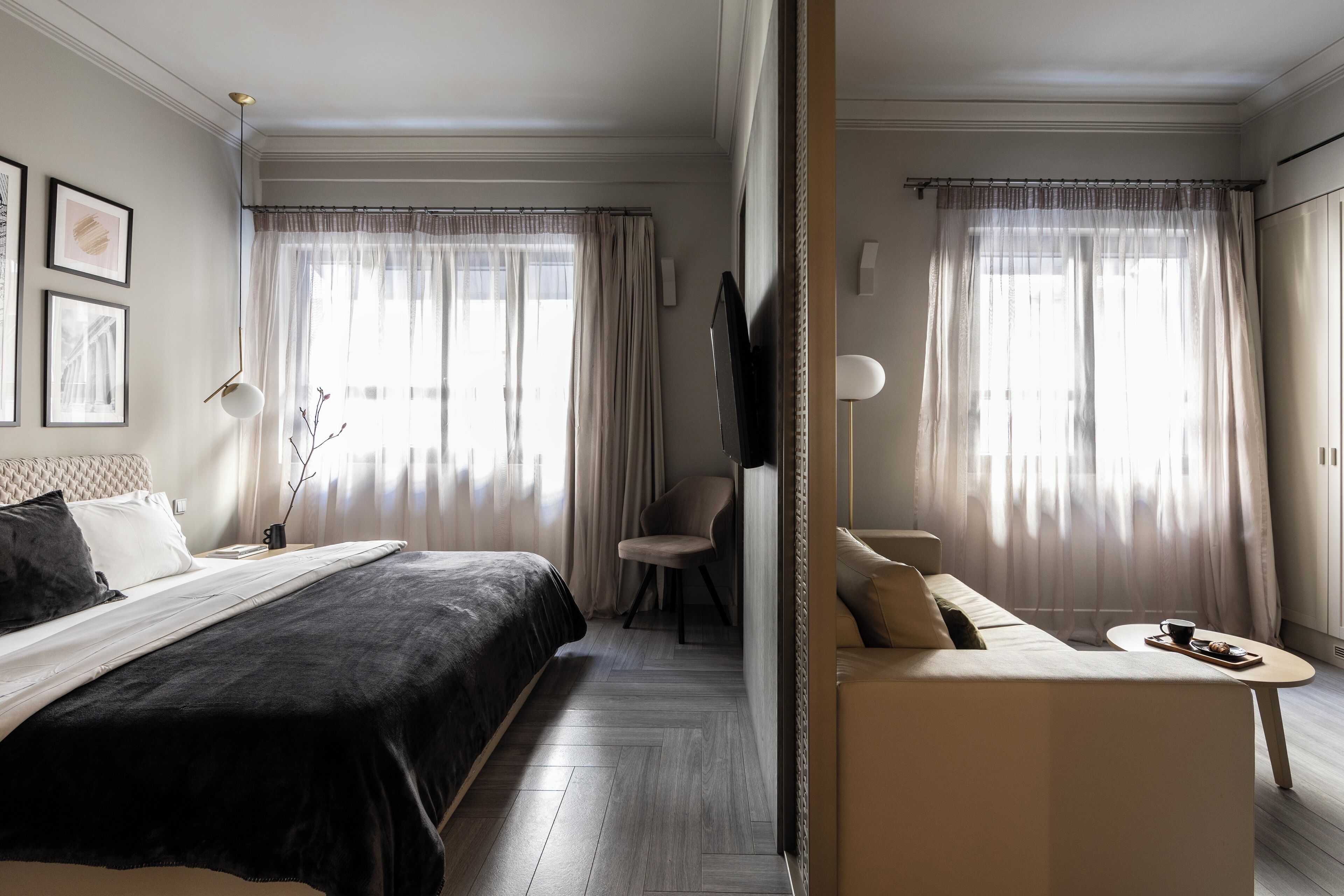 A hotel room with a bed, a sofa, a small table, and a TV.