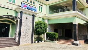 A hotel with a sign reading "MILESTONE SUITES" and a visible entrance with steps leading up to the door. - Milestone Hotel Annex (Lekki)