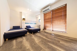 A modern bedroom with two beds, a potted plant, and a large window with blinds. - Guest House Megu-chan (Osaka)