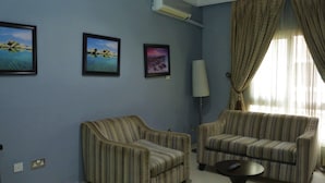 A living room with two striped sofas, a lamp, and three framed pictures on the wall. - Olive Branch Hotel (Port Harcourt)