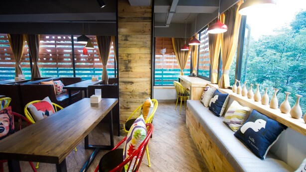 Un interior moderno con muebles de madera, una mesa larga y un banco con cojines.