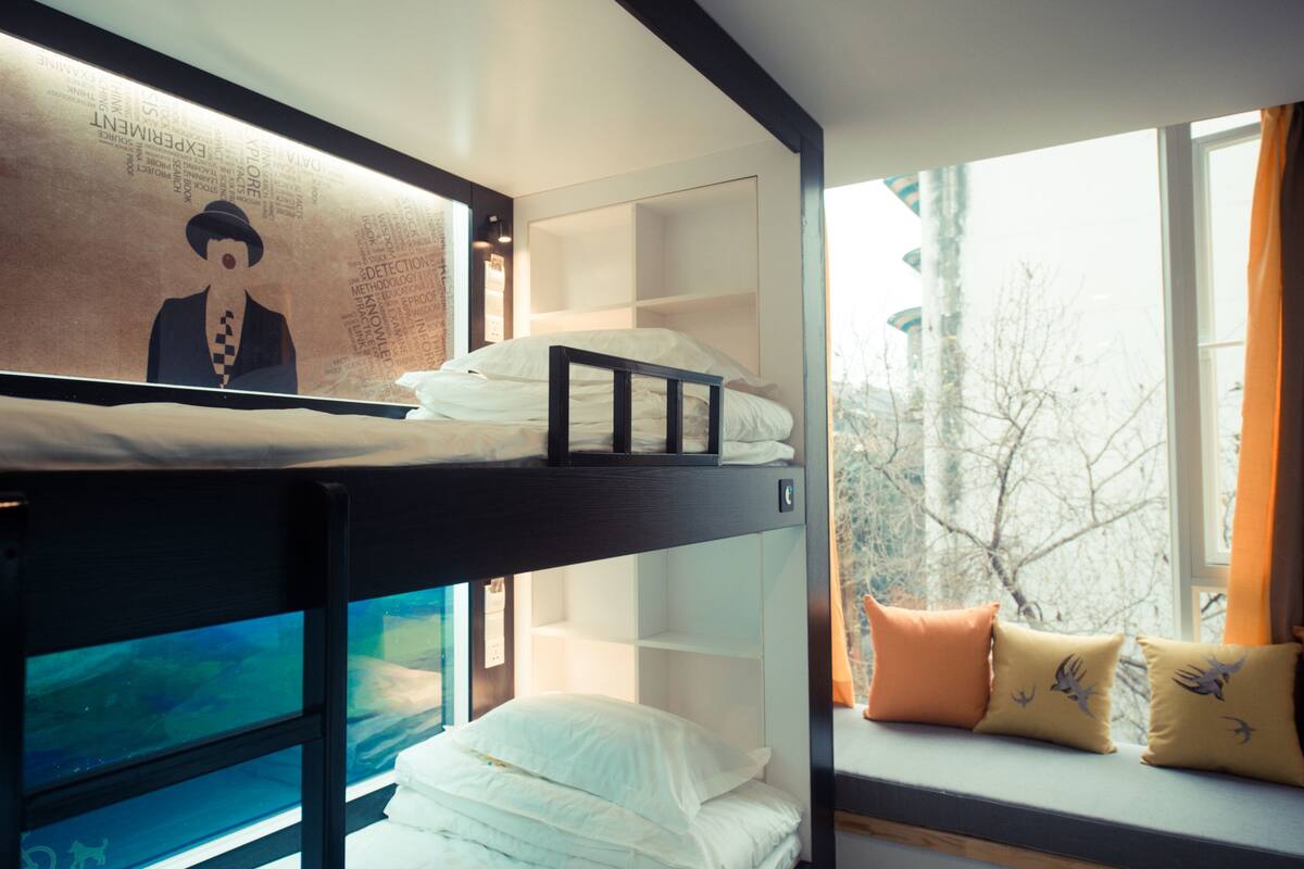A bunk bed room with a window seat and a wall art piece.