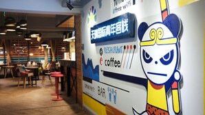 Interior de un restaurante con un mural de un personaje de caricatura, un letrero que anuncia wifi gratis y una zona de bar.