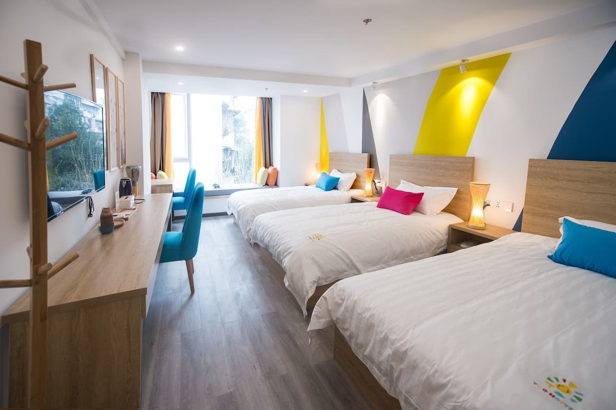 A hotel room with two beds, a desk, and a chair.