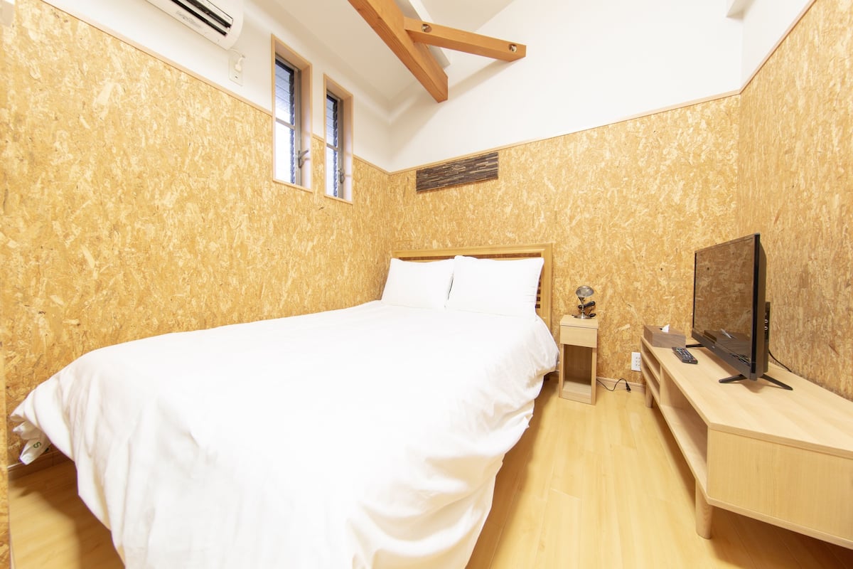 A bedroom with a bed, a TV, and a desk.