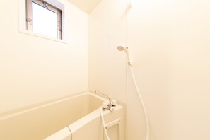 A bathroom with a bathtub, a shower, and a window. - Guest House ICHIKA (Kyoto)