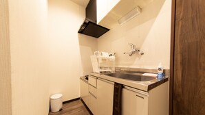A compact kitchen with a sink, a dish rack, and a trash bin. - Guest House ICHIKA (Kyoto)