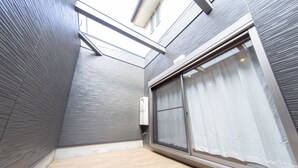 A modern interior with a large sliding glass door, a ceiling with skylights, and a wall-mounted air conditioning unit. - Guest House ICHIKA (Kyoto)