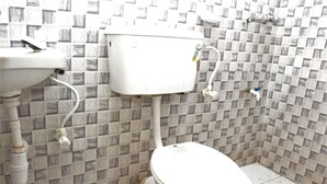 Et badeværelse med toilet, håndvask og flisebeklædte vægge.