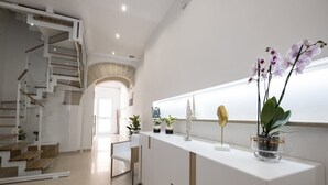 A modern interior with a staircase, a white reception desk, and potted plants. - Imera B&B (Favignana)