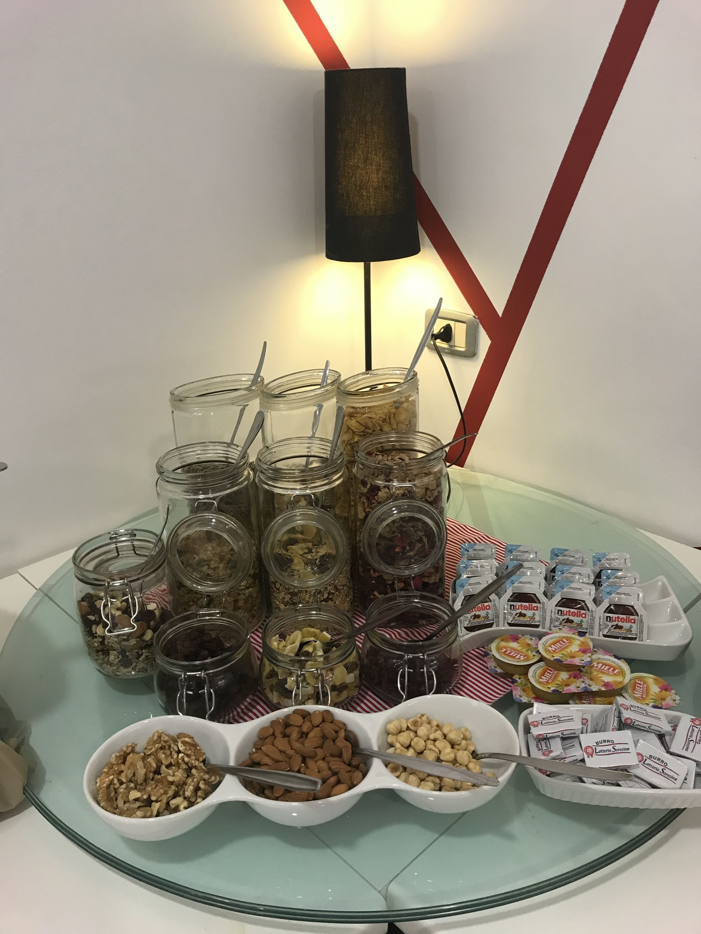 A buffet table with various food items including jars of nuts, cereals, and packaged snacks.