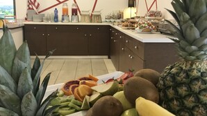 Une cuisine avec un présentoir de fruits, comprenant des ananas, des kiwis et des bananes.
