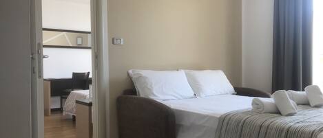 A hotel room with a bed, a desk, and a chair.