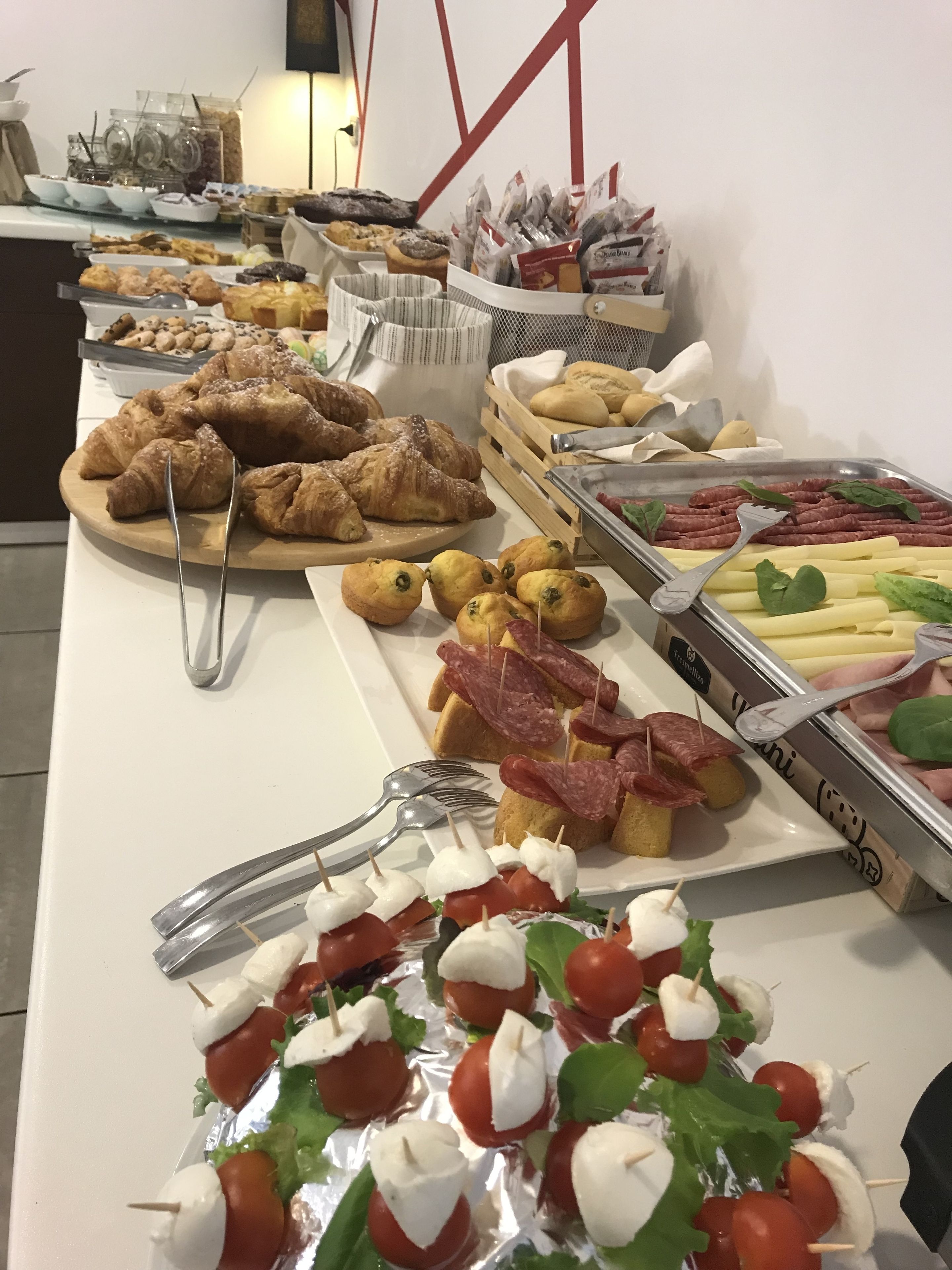 Un buffet proposant une variété de plats, notamment des pâtisseries, des viandes et des fromages.