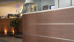 Un salon moderne avec un séparateur en bois, une machine à café, une lampe et une plante en pot.