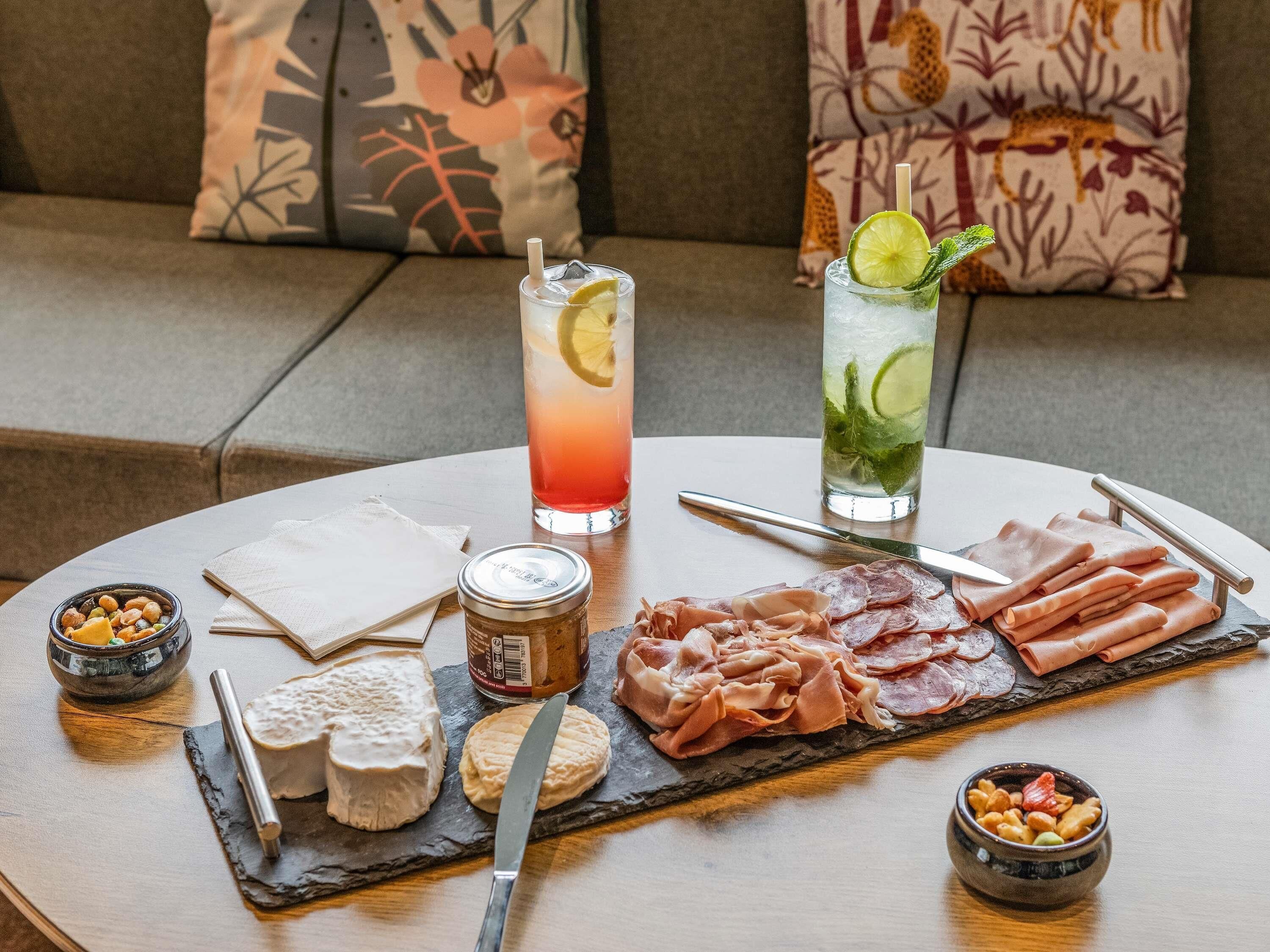 Ein Tisch mit einer Auswahl an Speisen, darunter Käse, Wurstwaren, Nüsse und verschiedene Getränke.