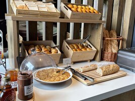 Un bufé de desayuno con panes, pasteles y diversas opciones para untar.