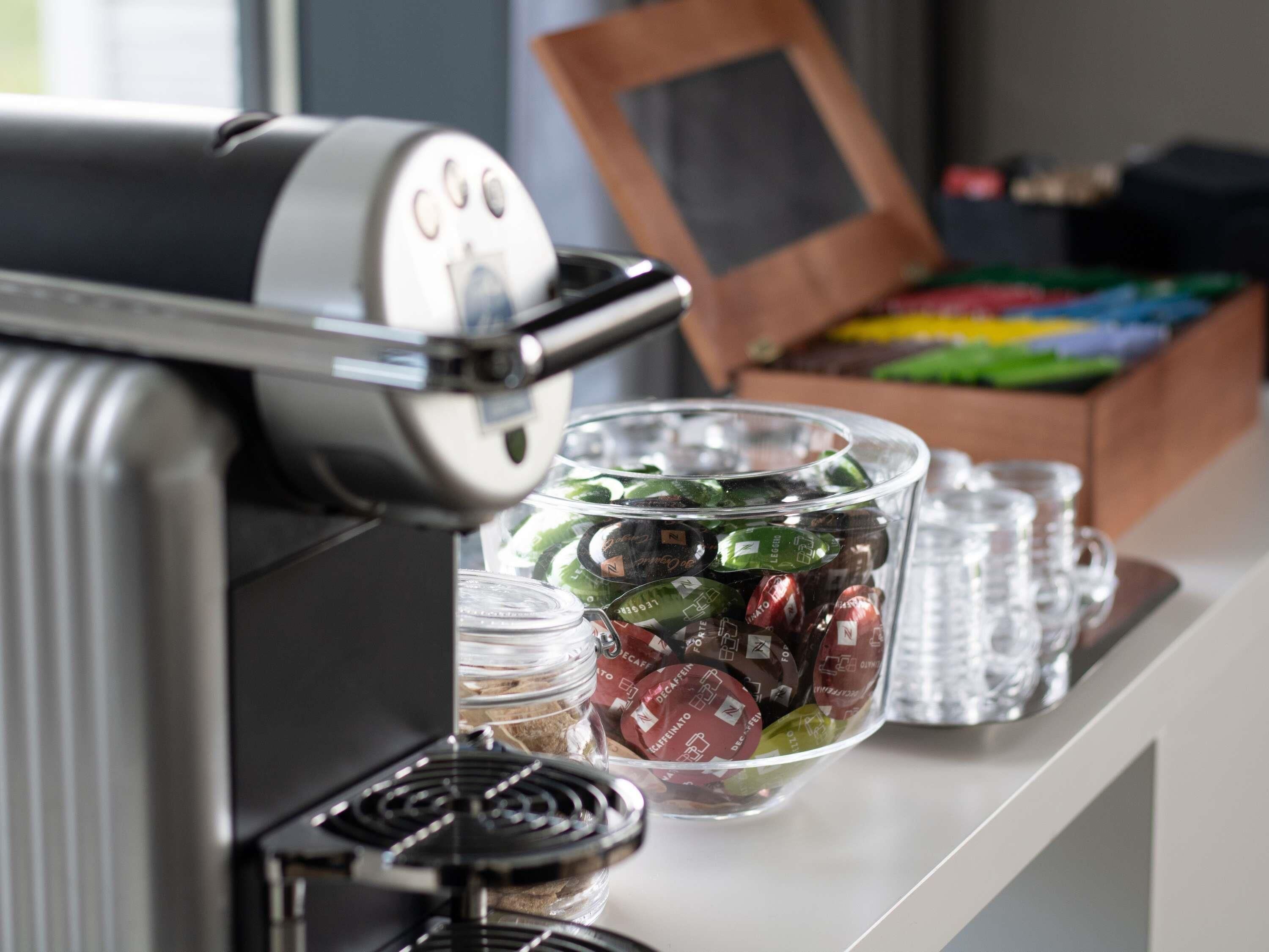 Máquina de café com recipiente de vidro cheio de cápsulas.