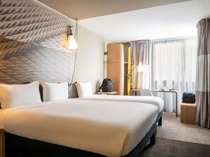 A hotel room with two beds, a desk, a chair, a lamp, and a window with curtains. - ibis Gonesse Le Bourget (Gonesse)