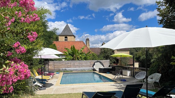 A backyard with a swimming pool, lounge chairs, umbrellas, and a small table. - Gîte 5p, 3*, Lascaux Périgord Noir, wifi parc Spa piscine chauf ok dog & cat (Montignac-Lascaux)