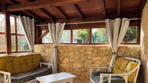 A rustic room with stone walls, wooden beams, and white wicker furniture. - Gîte 5p, 3*, Lascaux Périgord Noir, wifi parc Spa piscine chauf ok dog & cat (Montignac-Lascaux)