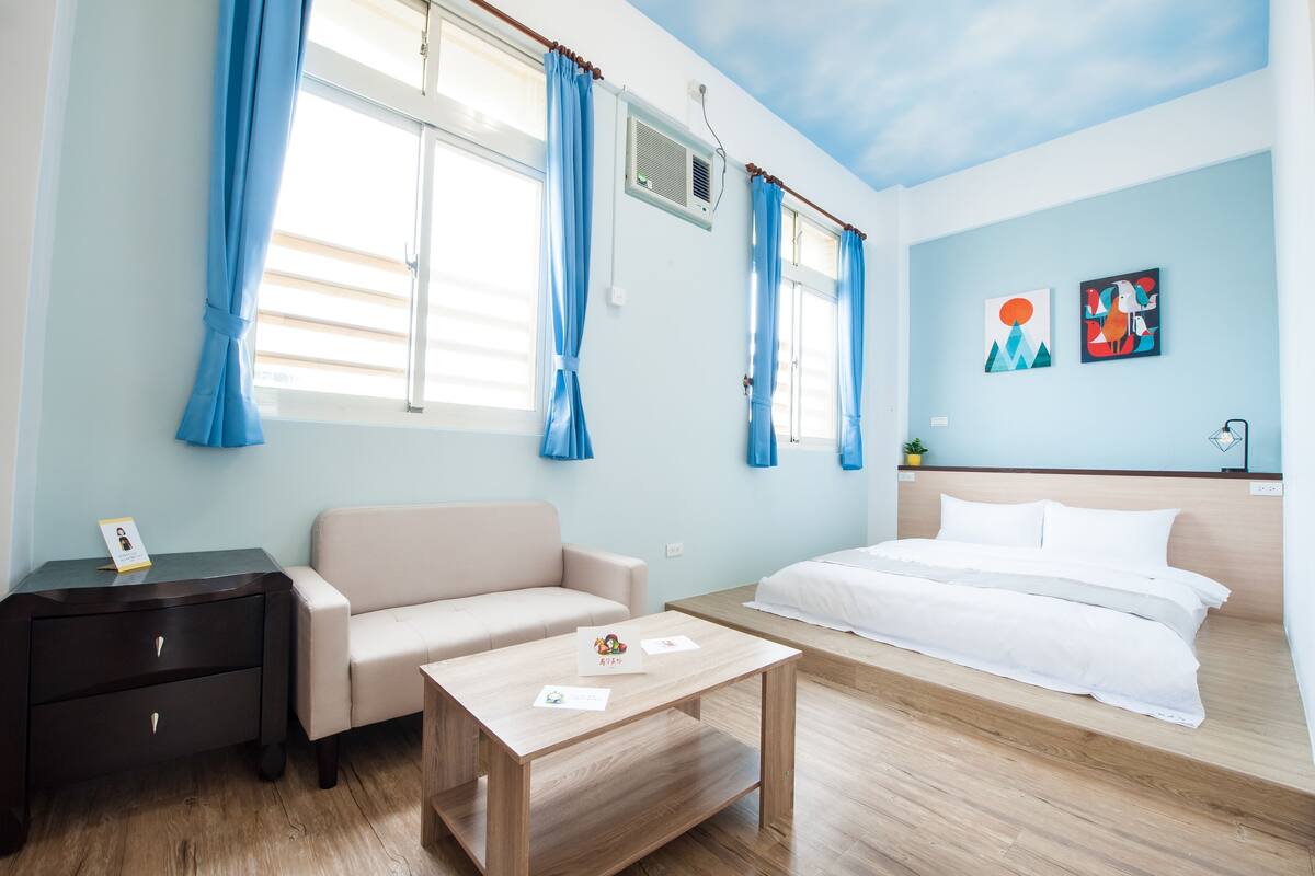 A hotel room with a bed, a sofa, a desk, and a small table.