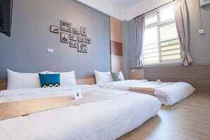 A hotel room with two beds, a wall with framed pictures, a window with curtains, and a wooden floor. - Penghu D.C. Inn (Magong)