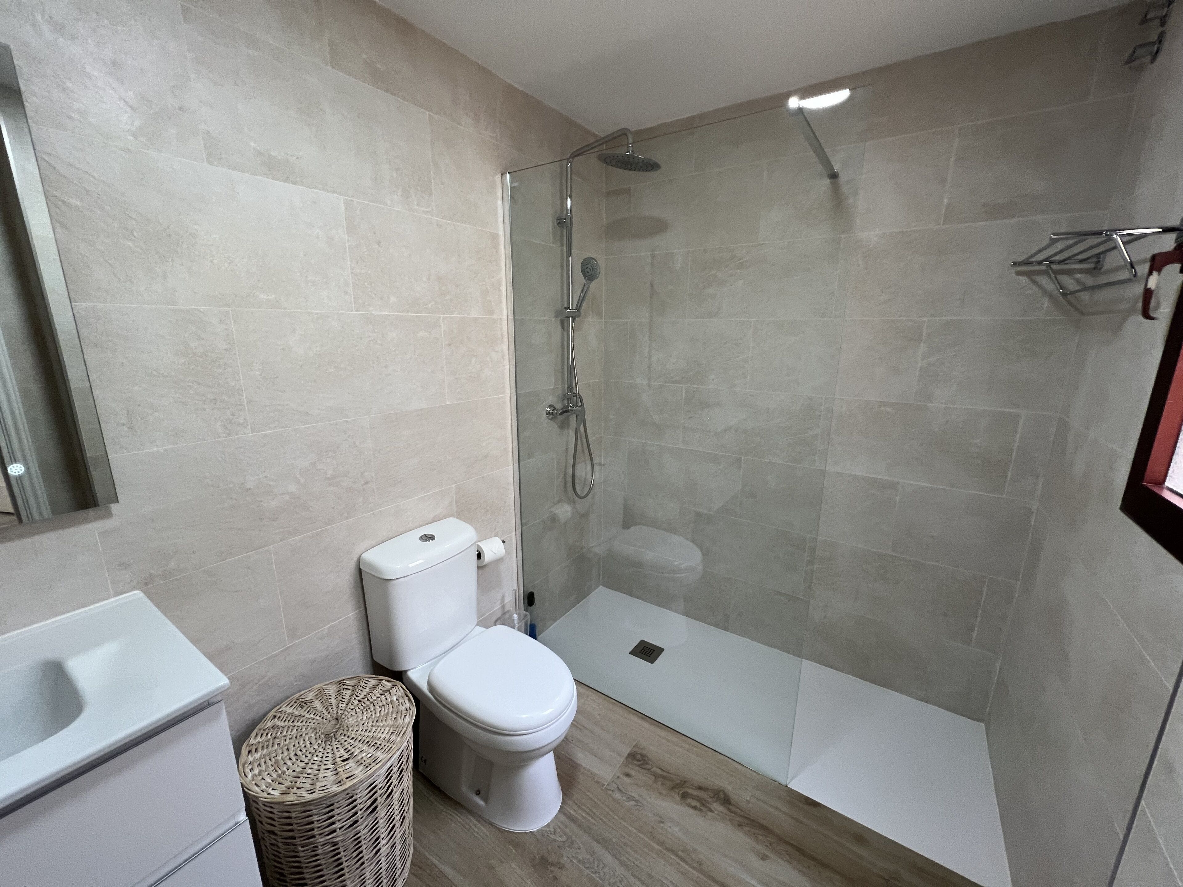 A modern bathroom with a glass-enclosed shower, a toilet, and a sink.