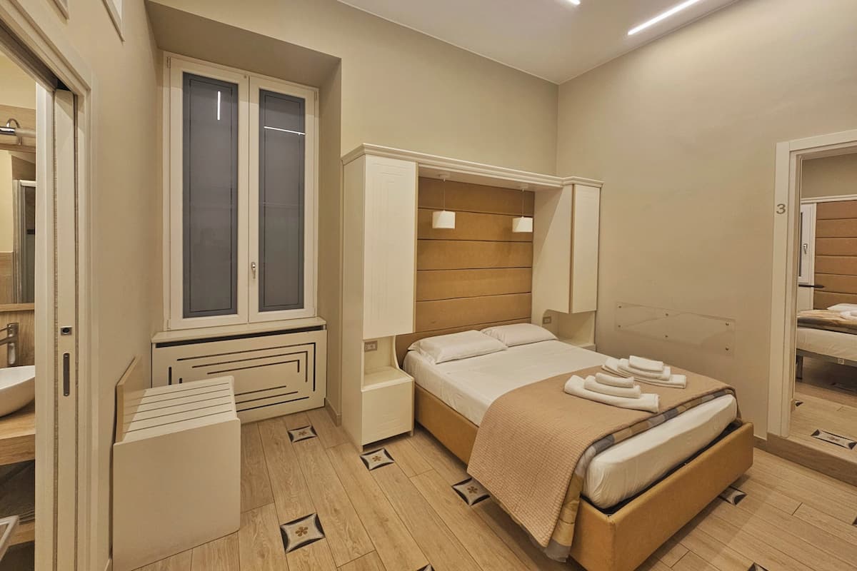 Ein Schlafzimmer mit Bett, Nachttischen, einem Kleiderschrank und einem Fenster.