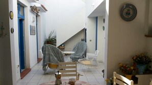 A cozy dining area with a table set for two, surrounded by chairs, a staircase, and a potted plant. - Mediterranea Guesthouse B&B (Portopalo di Capo Passero)