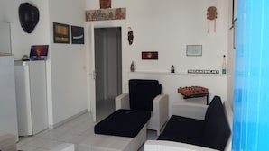 A living room with a sofa set, a small table, and a decorative wall piece. - Mediterranea Guesthouse B&B (Portopalo di Capo Passero)