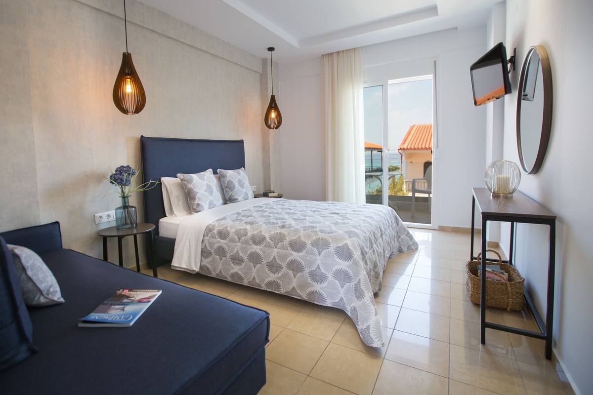 Una camera da letto moderna con un letto, un divano, un comodino, una lampada e vista all'esterno.