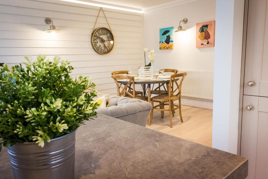 A dining area with a round table, wooden chairs, and a potted plant.