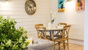 A dining area with a round table, wooden chairs, and a wall-mounted clock. - The Bay Colwell (Freshwater)