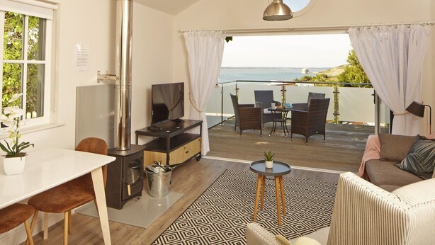 A cozy room with a kitchen, dining area, and a balcony with a view of the sea. - The Bay Colwell (Freshwater)