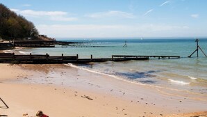 A beach with a wooden pier extending into the water, a sandy shore, and a clear blue sky. - The Bay Colwell (Freshwater)