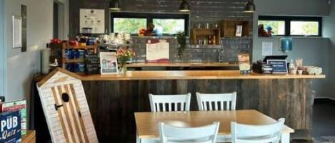 A modern kitchen with a central island, pendant lighting, and a dining area with white chairs.