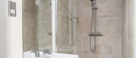 Un bagno moderno con cabina doccia in vetro, un mobile lavabo bianco e uno specchio grande.
