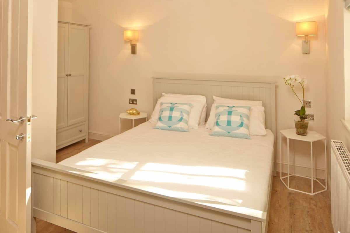 A bedroom with a bed, bedside tables, a nightstand, a radiator, and a wardrobe.