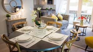 A dining area with a round table set for four, a sofa, and a kitchen in the background. - The Bay Colwell (Freshwater)