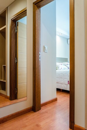 A bedroom with a wooden door, a bed with a white duvet, and a nightstand. - Hotel Boutique Sofia Soberana (Bahia Blanca)