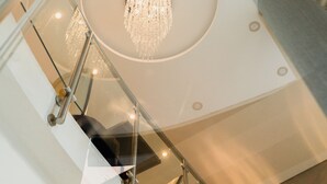 A modern interior with a glass railing, a central chandelier, and a circular ceiling design. - Hotel Boutique Sofia Soberana (Bahia Blanca)