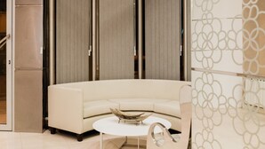 A modern interior with a curved sofa, a round coffee table, and a decorative wall panel. - Hotel Boutique Sofia Soberana (Bahia Blanca)
