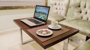 A laptop on a table with a cup of coffee and a plate of pastries. - Hotel Boutique Sofia Soberana (Bahia Blanca)