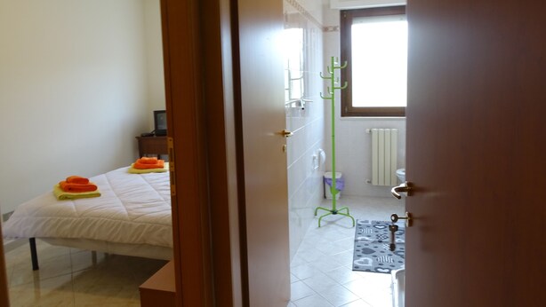 Quarto com cama, mesa de cabeceira e janela.