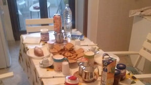 Uma mesa de jantar com toalha de mesa estampada com girassóis, diversos alimentos e utensílios de cozinha.